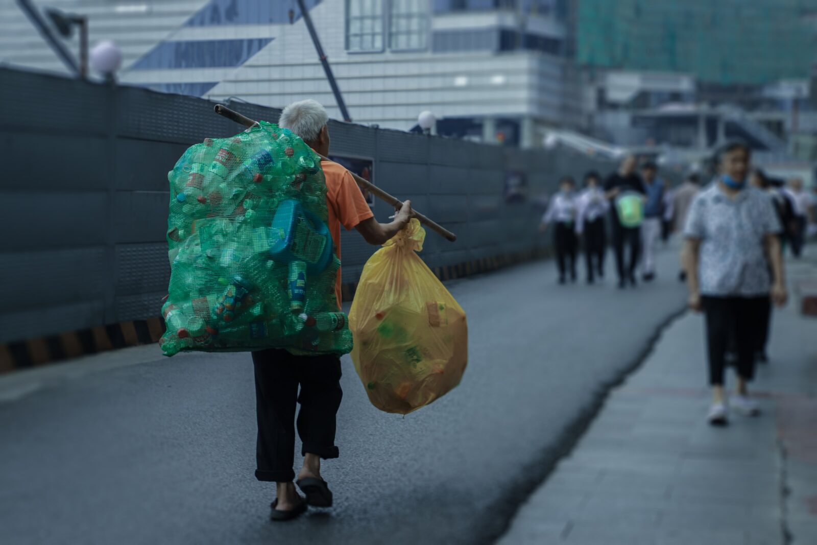 Sustainability strategies | A man carrying bags full of used plastic bottles on a busy road.